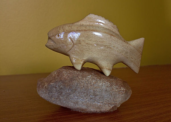 whittles carved fish in wood